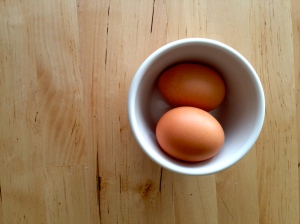 two brown organic eggs in a white bowl